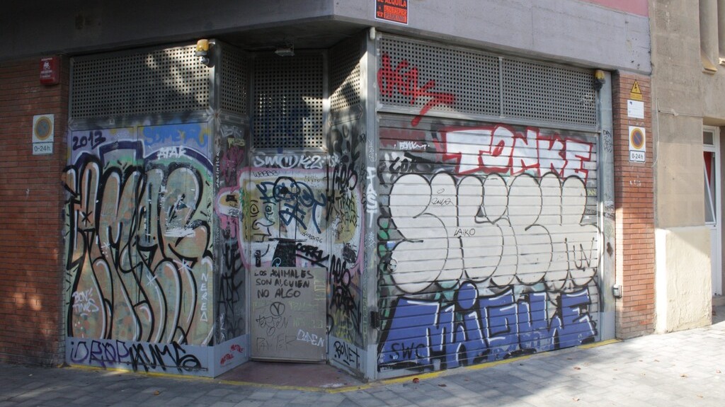 Antes y después - Estado original - Decoración graffiti puertas PARKING con PAISAJE NATURALEZA o URBANO en Barcelona